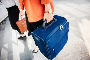 Personal Image Consultant Beth Divine recommends packing a spare outfit in your carry-on luggage image shows person holding blue suitcase